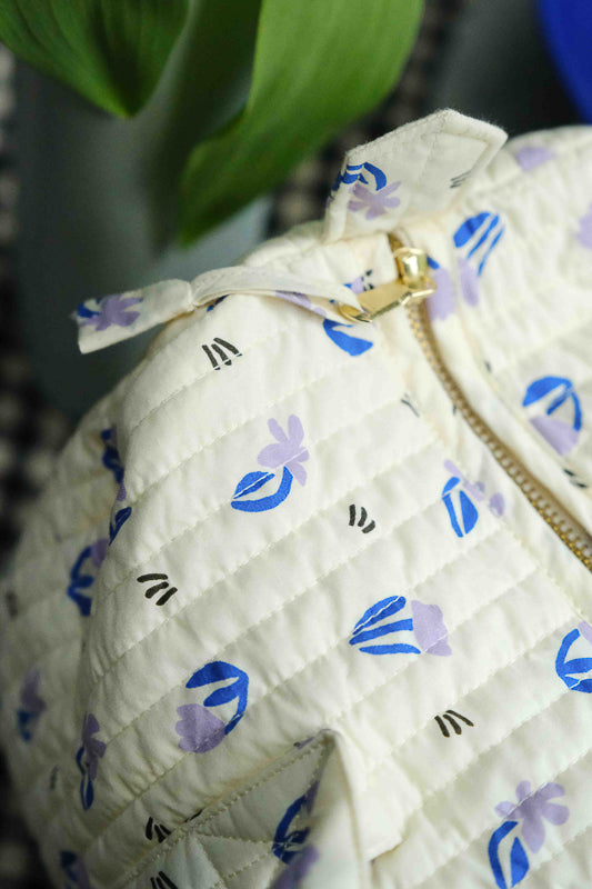Détail du tissu et de la fermeture du sac weekend en coton matelassé imprimé little flower, petites fleurs lilas sur fond beige. Sac de voyage et accessoire de mode pour femme en coton.