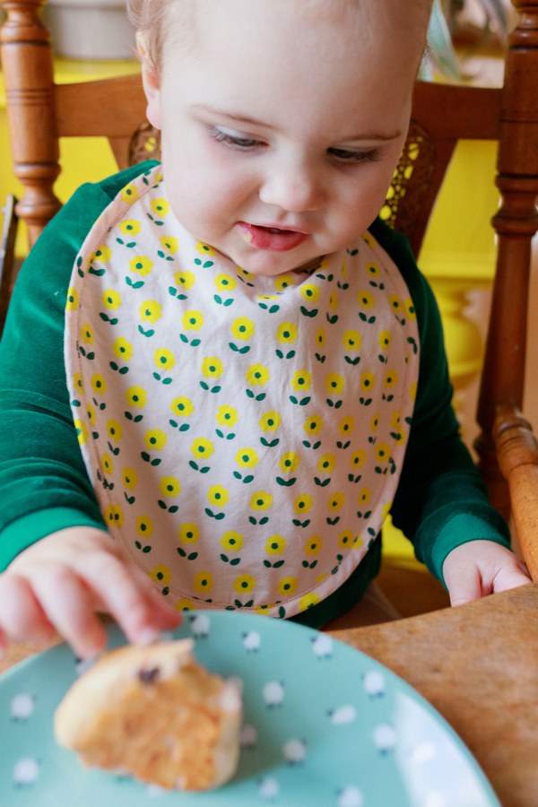 Bébé qui mange protégé par son bavoir en coton bio de la collection bébé naissance Baby Care imprimé fleur