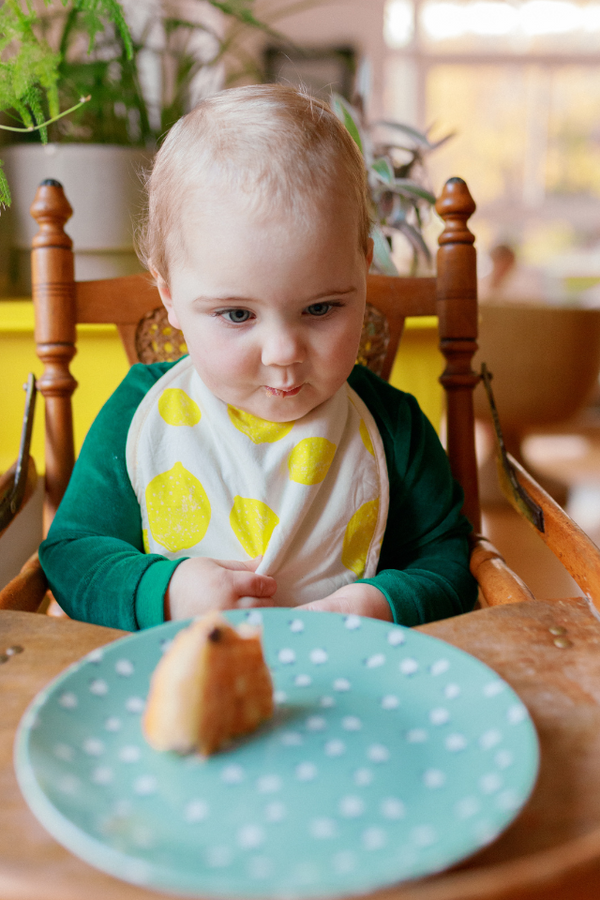Bébé qui mange protégé par son bavoir en coton bio de la collection bébé naissance Baby Care imprimé citron